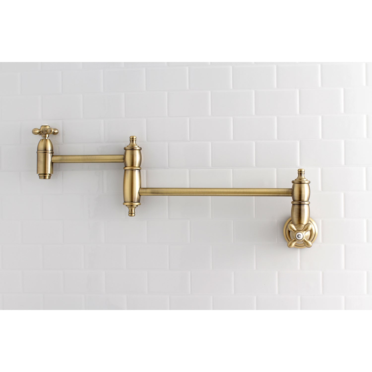 Kingston Brass KS3103AX Restoration Wall Mount Pot Filler Faucet, Antique Brass mounted on white tiled wall.