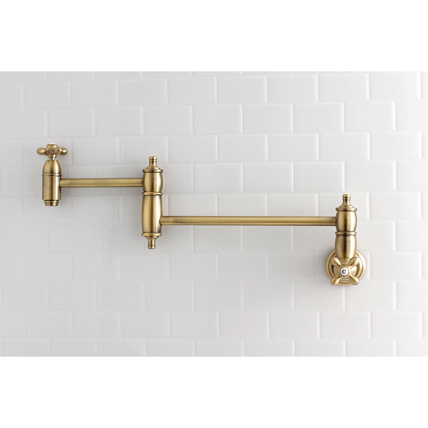 Kingston Brass KS3103AX Restoration Wall Mount Pot Filler Faucet, Antique Brass mounted on white tiled wall.