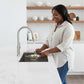 Woman straining vegetables in a Stylish Azuni 28" undermount stainless steel sink in a white kitchen