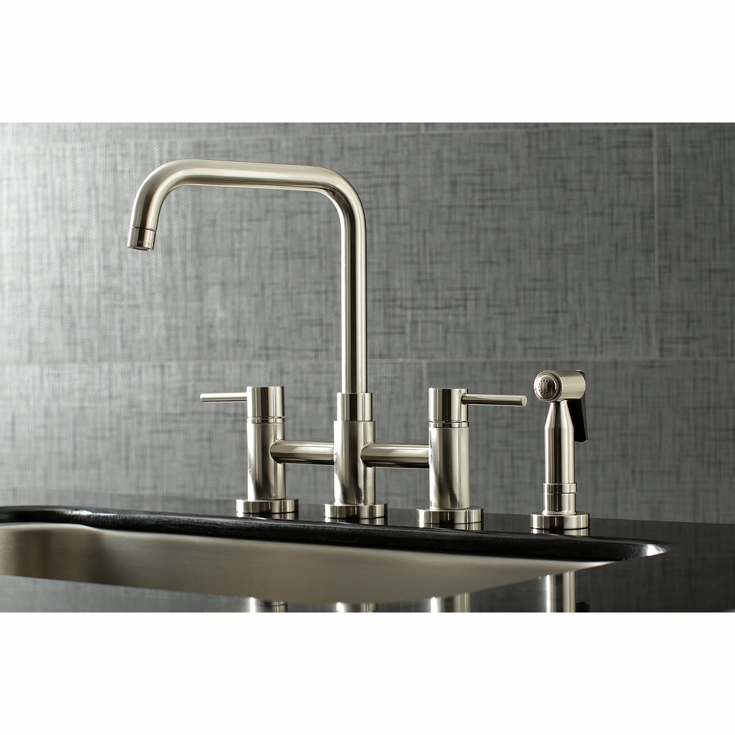 Kingston KS8287DLBS Concord Bridge Kitchen Faucet with Brass Sprayer, Brushed Brass on a black sink.