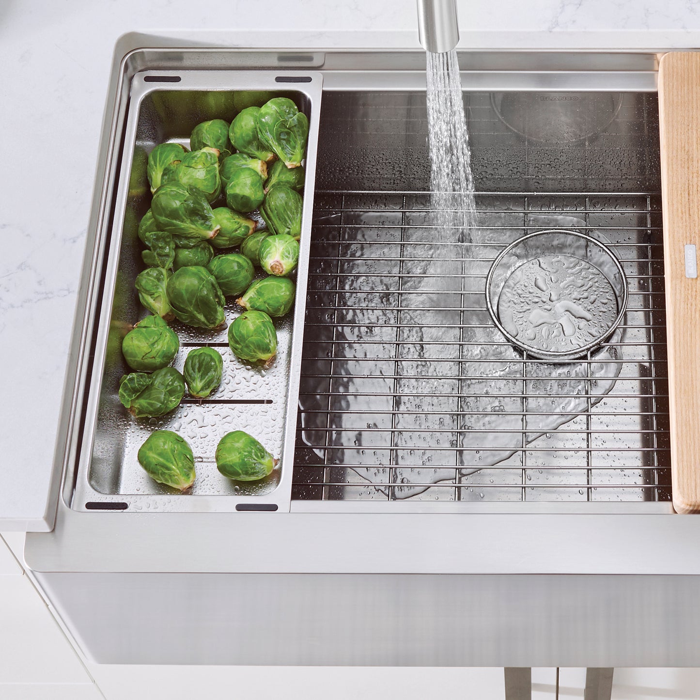 BLANCO Quatrus Ergon Colander featuring rinsing brussels sprouts in stainless steel integrated ledge sink.
