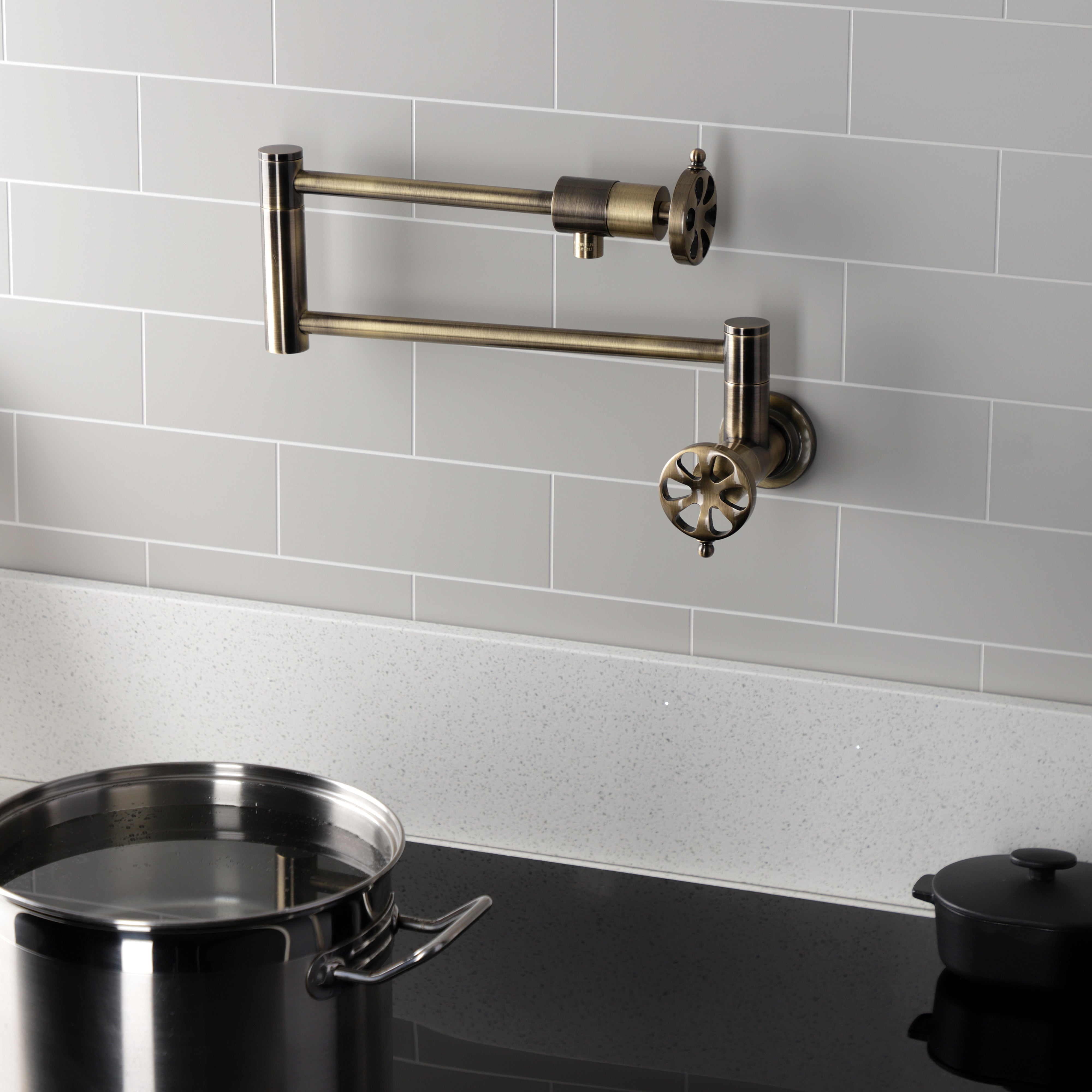 Kingston Brass KS4103RX Belknap Wall Mount Pot Filler Faucet, Antique Brass with pot and cooking surface.