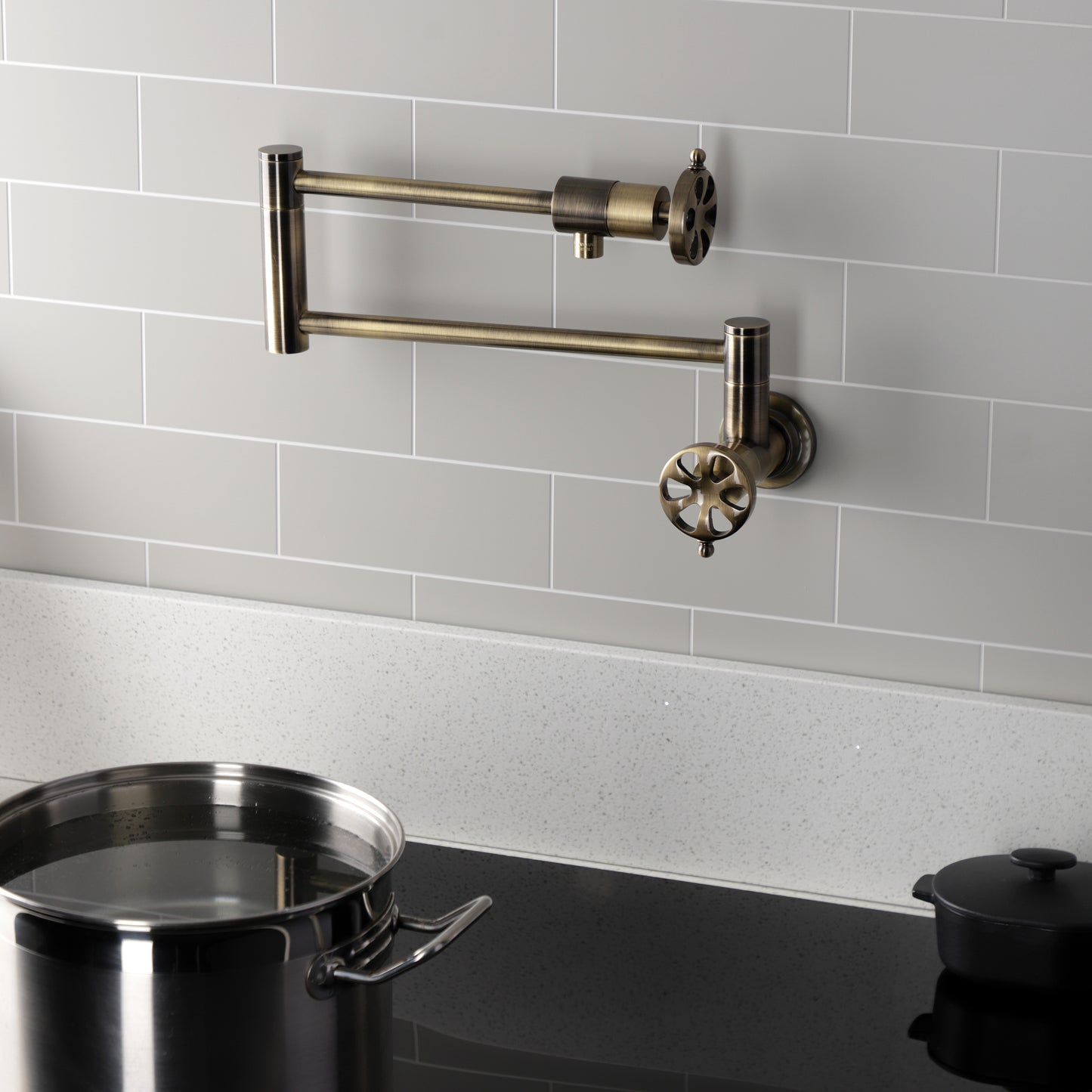 Kingston Brass KS4103RX Belknap Wall Mount Pot Filler Faucet, Antique Brass with pot and cooking surface.
