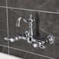 Kingston KS2443TAL Tudor Two-Handle Wall Mount Bridge Kitchen Faucet, Antique Brass in chrome finish against gray tile.