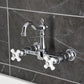 Kingston KS2443PX Heritage Two-Handle Wall Mount Bridge Kitchen Faucet, Antique Brass on a dark tiled wall.