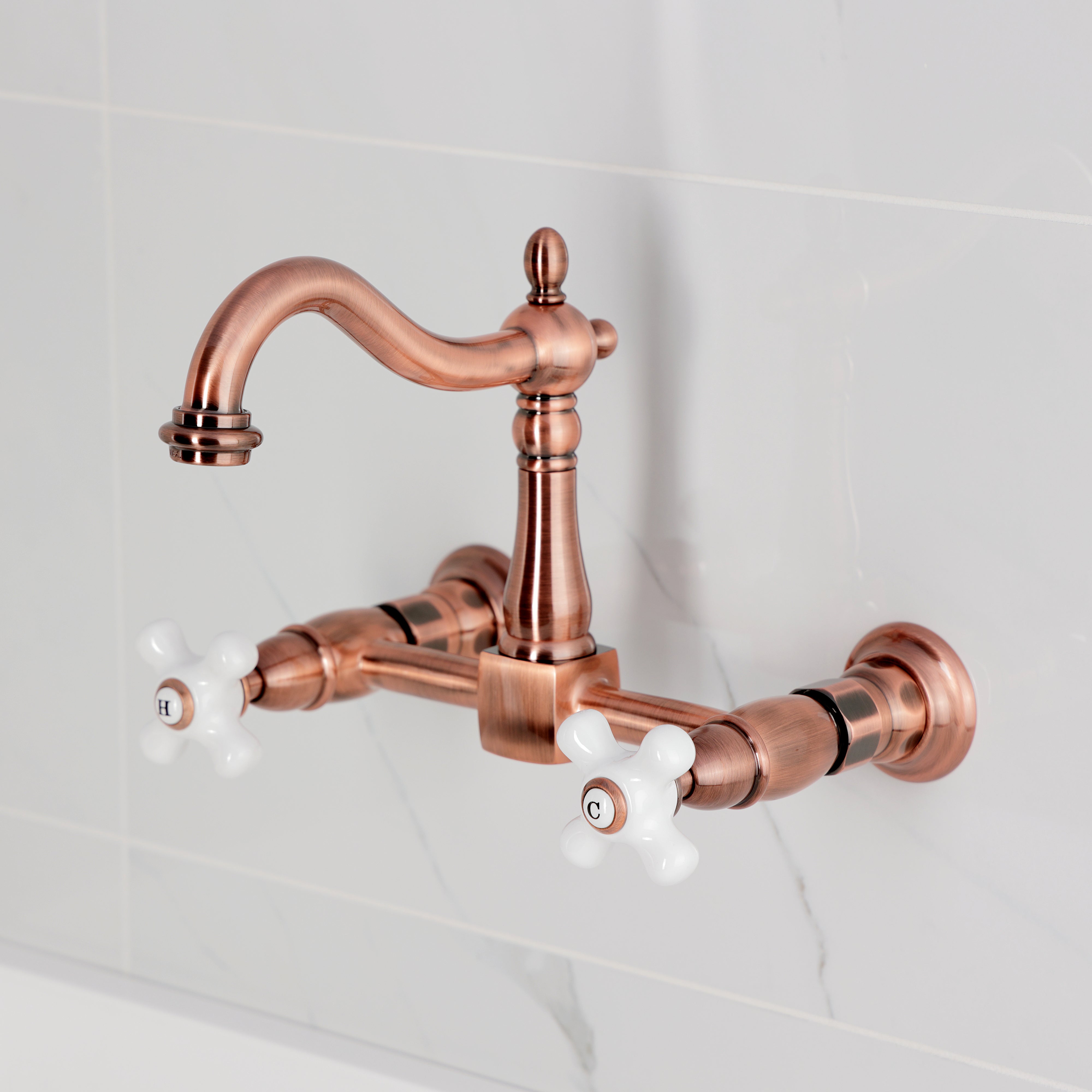 Kingston KS1263PX Heritage Two-Handle Wall Mount Bridge Kitchen Faucet, Antique Brass with white knobs and elegant design.