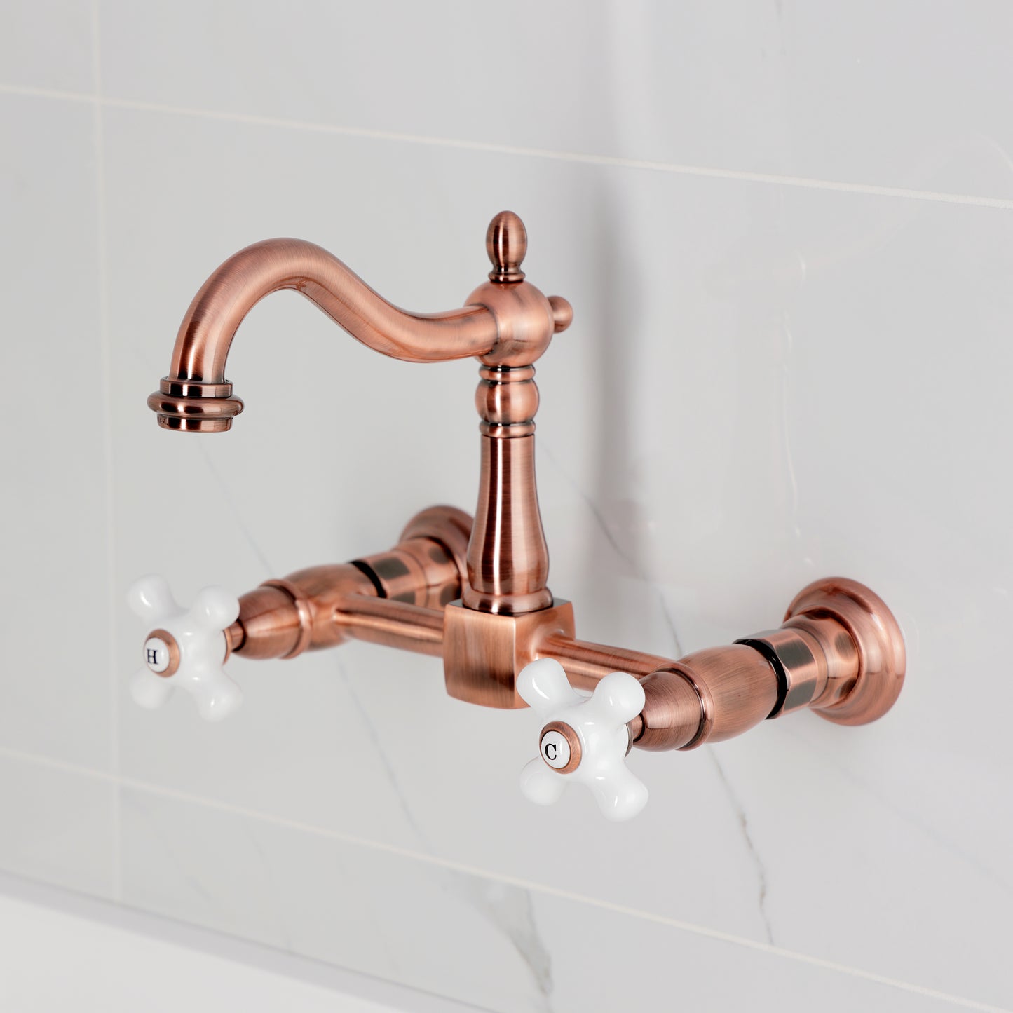 Kingston KS1263PX Heritage Two-Handle Wall Mount Bridge Kitchen Faucet, Antique Brass with white knobs and elegant design.