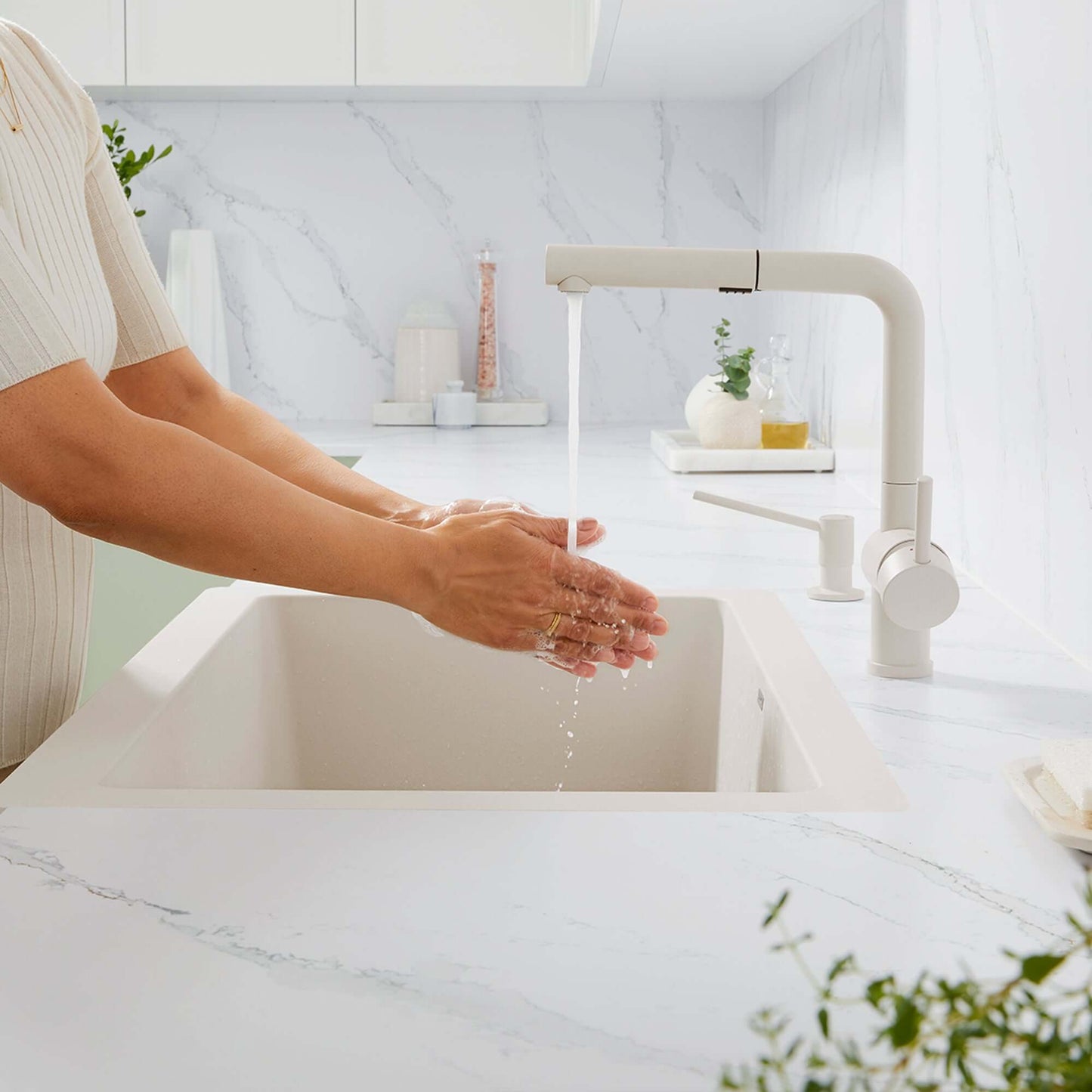 BLANCO Linus Low Arc Pull-Out Dual-Spray Kitchen Faucet -Soft White in a modern kitchen sink with hands washing.