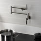Kingston Brass KS4103KL Whitaker Wall Mount Pot Filler Faucet, Antique Brass with foldable swing arms in kitchen.