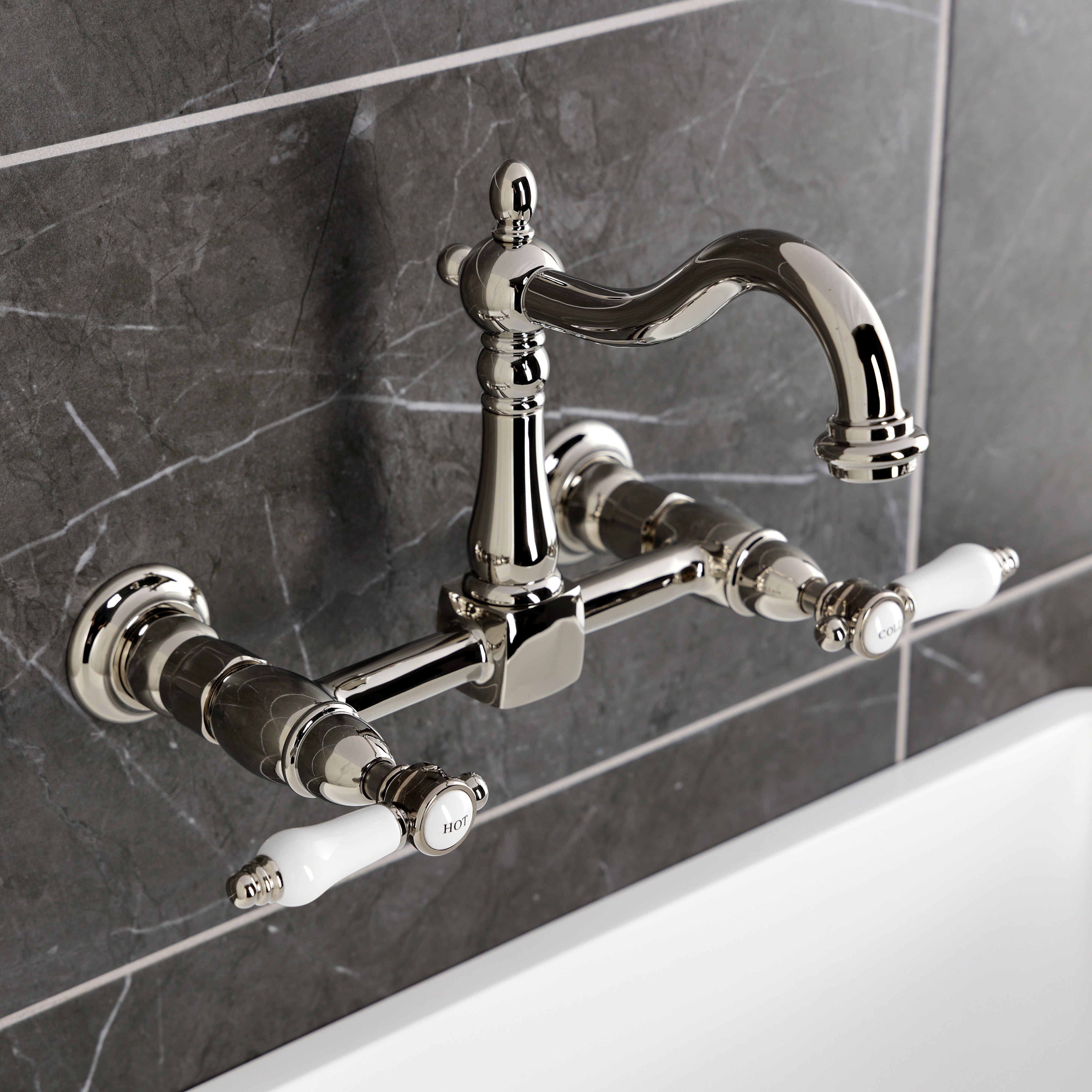 Kingston KS1263BPL Bel-Air Two-Handle Wall Mount Bridge Kitchen Faucet, Antique Brass with white porcelain levers.