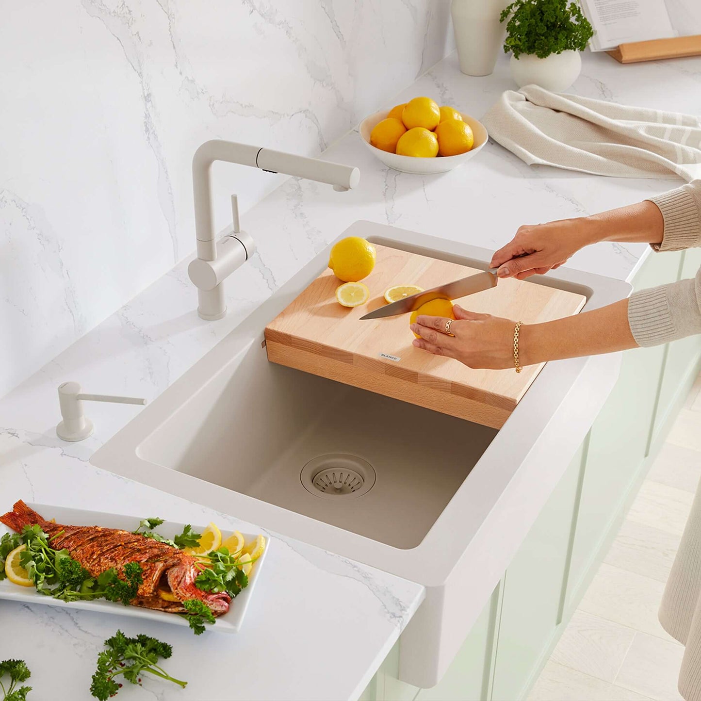 BLANCO Linus Low Arc Pull-Out Dual-Spray Kitchen Faucet - Soft White with wooden cutting board and lemons in kitchen sink.