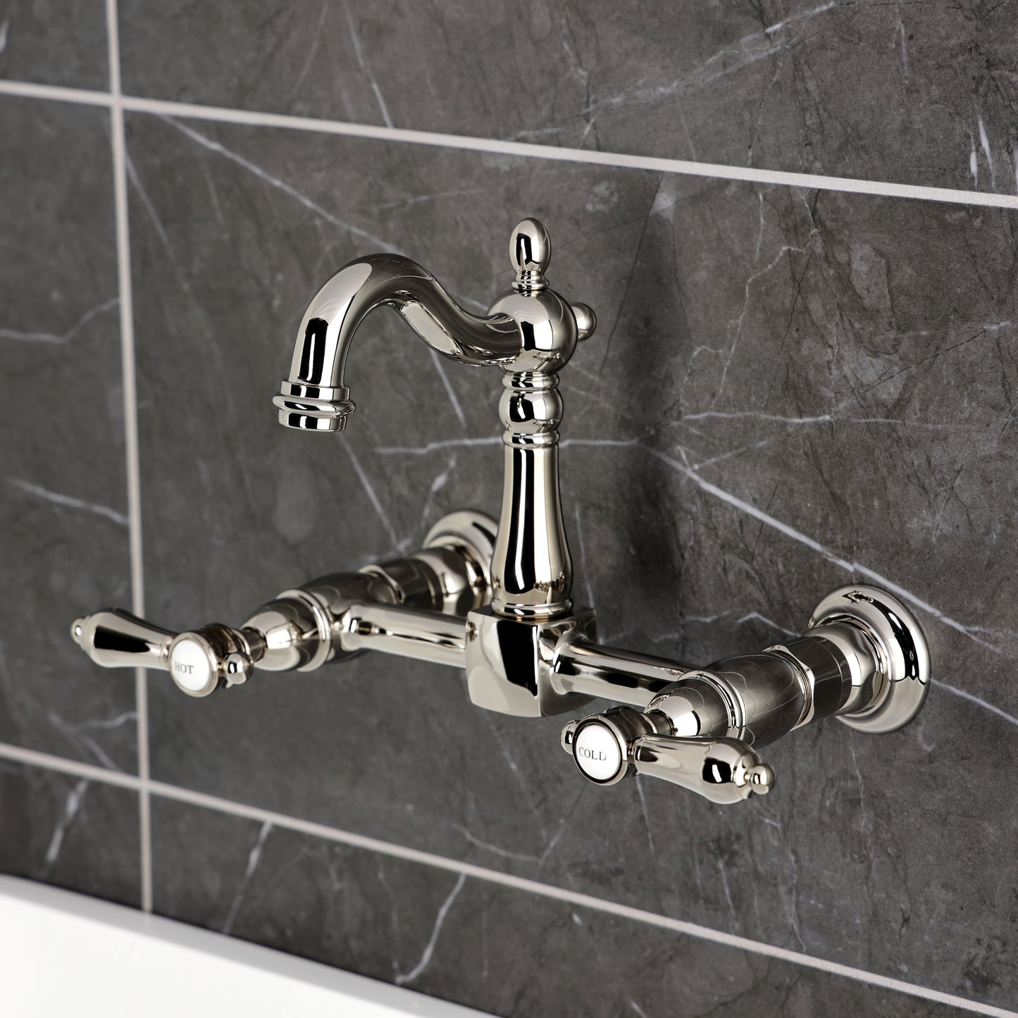 Kingston KS2443BAL Heirloom Two-Handle Wall Mount Bridge Kitchen Faucet, Antique Brass on a modern tiles background.