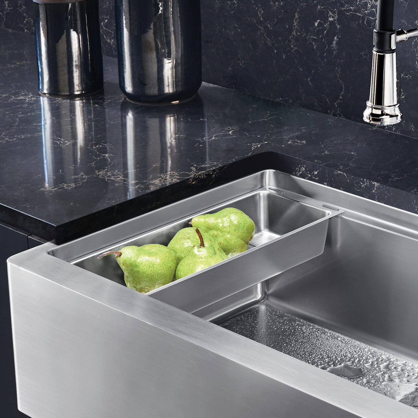 BLANCO Quatrus Ergon Colander holding green pears in a stainless steel sink with a dark countertop.