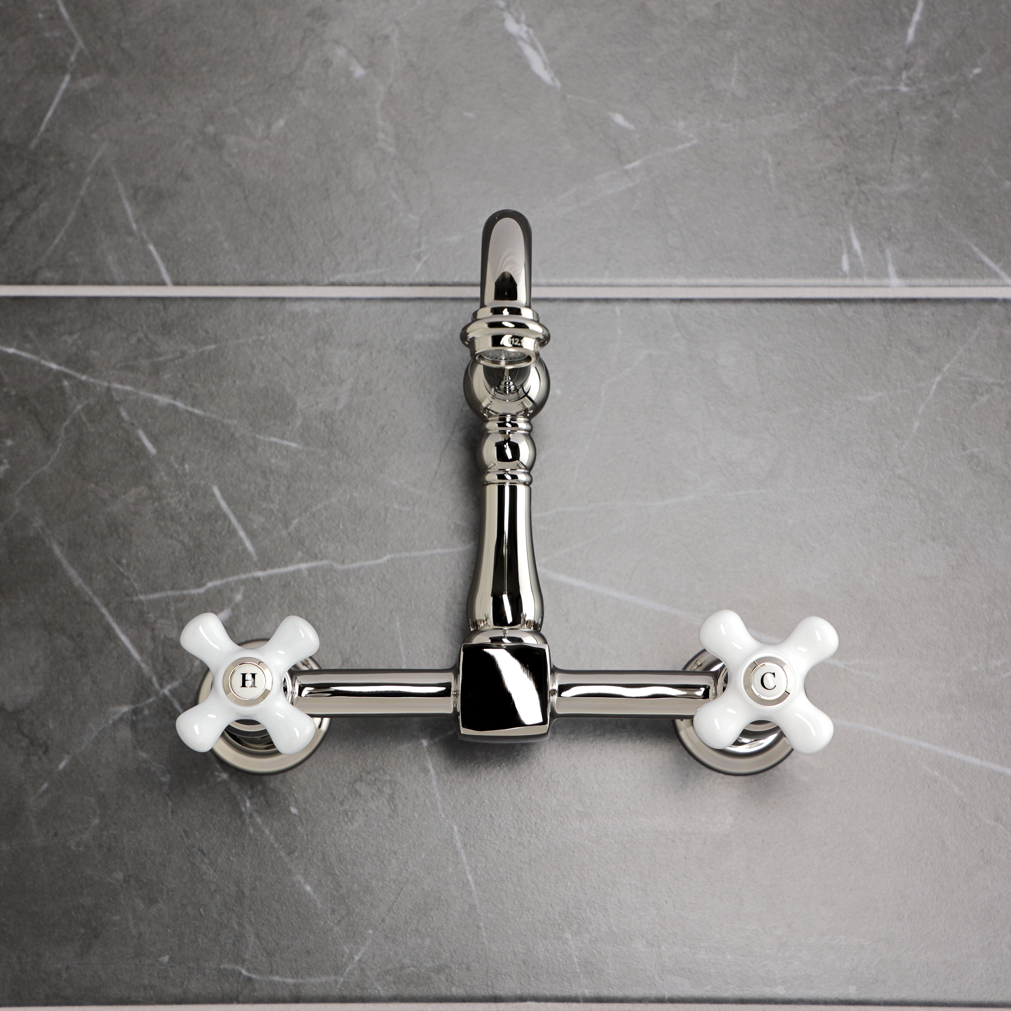 Kingston KS1263PX Heritage Two-Handle Wall Mount Bridge Kitchen Faucet, Antique Brass on a sleek gray backdrop.