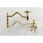 Kingston Brass KS2107AX Heritage Wall Mount Pot Filler Faucet, Brushed Brass with swing arms on a marble background.