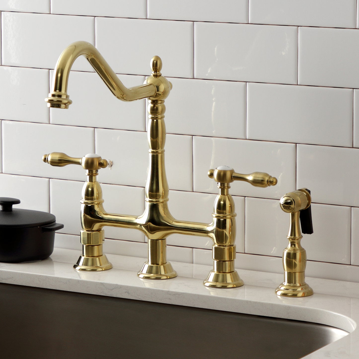 Kingston KS1273TALBS Tudor Bridge Kitchen Faucet with Brass Sprayer, Antique Brass on countertop.