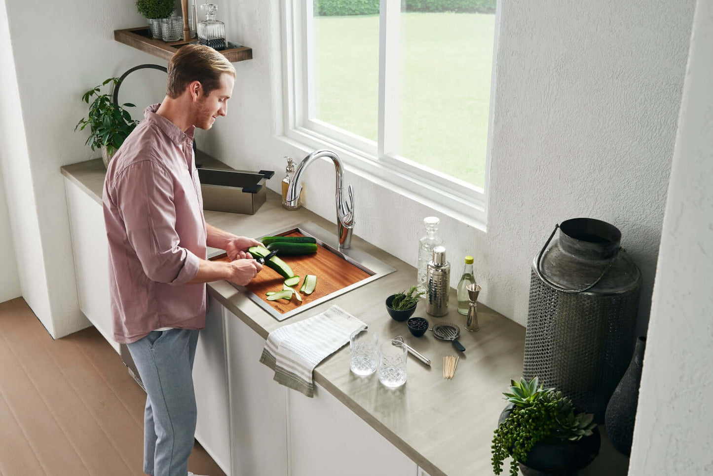 Man preparing vegetables at Ruvati Siena 21" RV Workstation Drop-in Stainless Steel Kitchen Sink RVH8221 in modern kitchen.