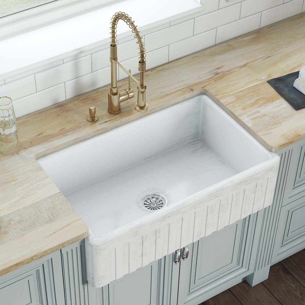 Ruvati Fiamma 33" Fireclay Reversible Kitchen Sink RVL2300SW installed in a stylish kitchen with a golden faucet.