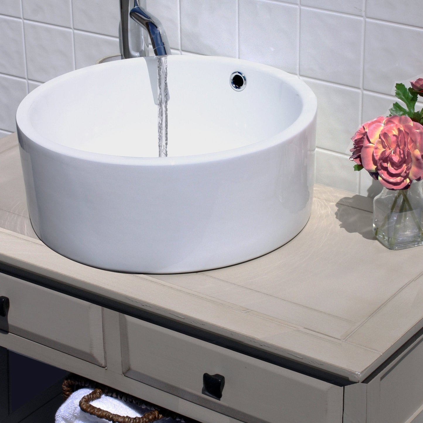 Nantucket Round  White Vessel Sink With Overflow - NSV213 displayed with water running and flowers in the background.