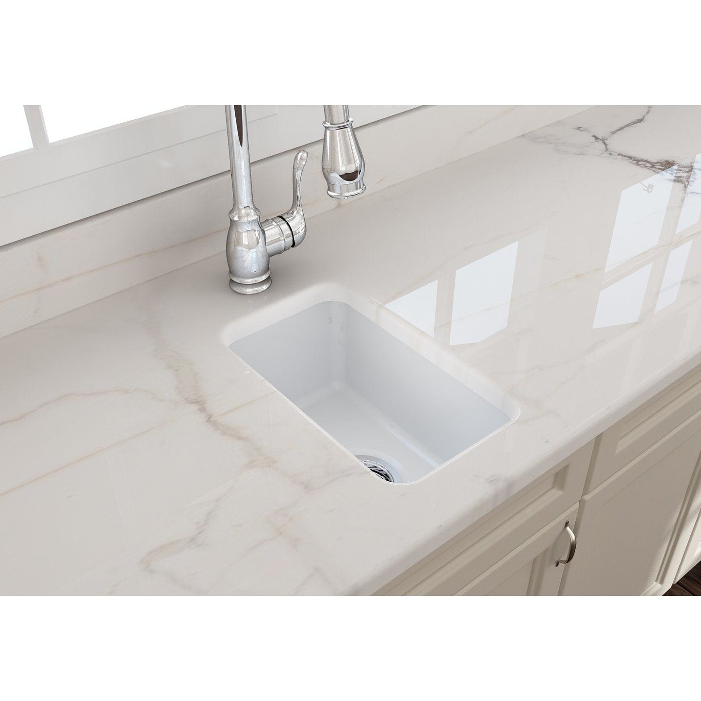 Top view of BOCCHI SOTTO 12" Fireclay Modern Undermount Single Bowl Bar Sink with Strainer in white on a marble countertop.